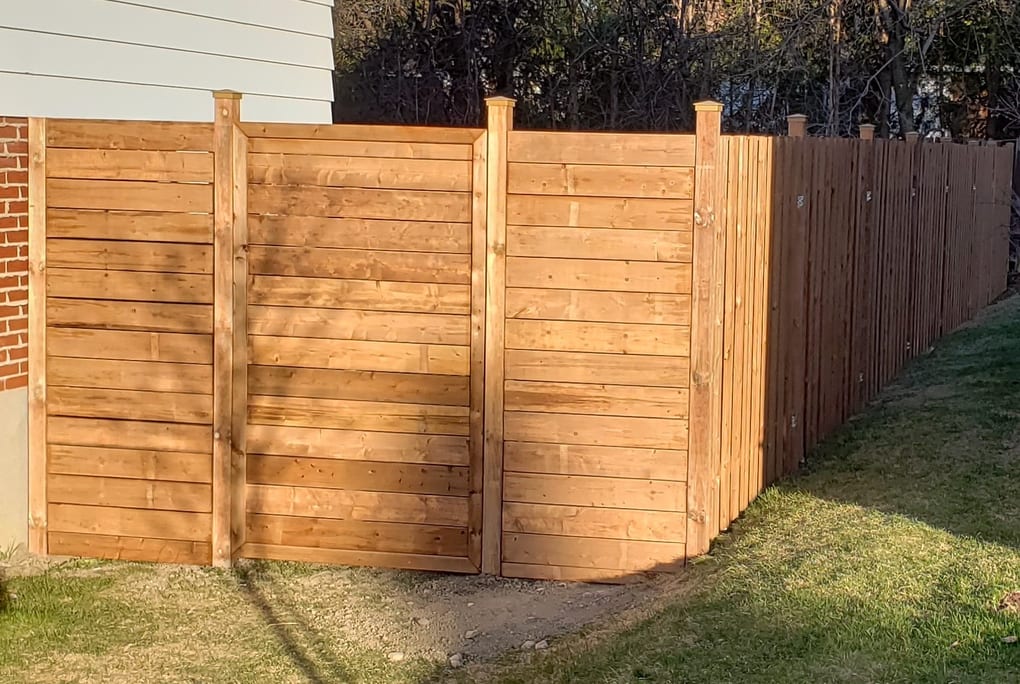 After: new cedar fence with a horizontal-slat gate panel running along the property line